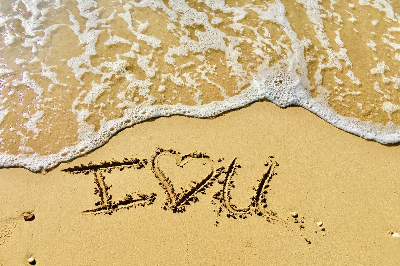 aerial photo of I love you text on sand at the seashore