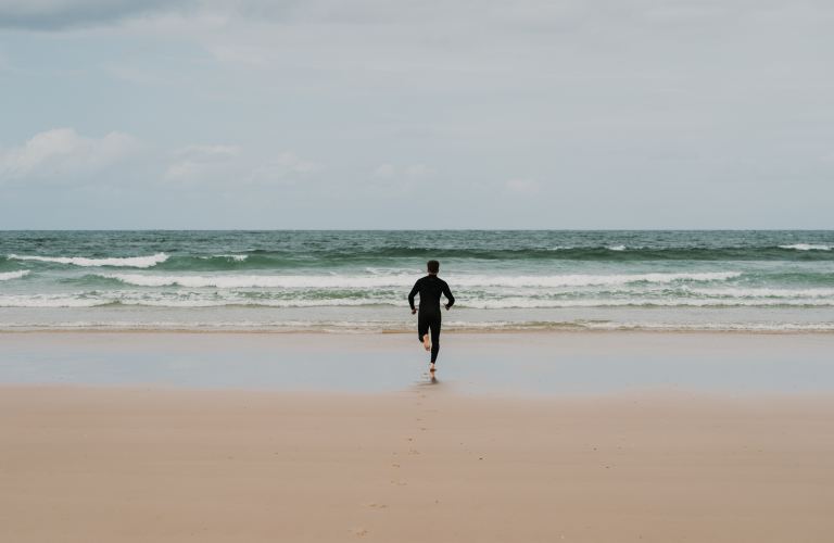 man in black shirt walking on beach during daytime