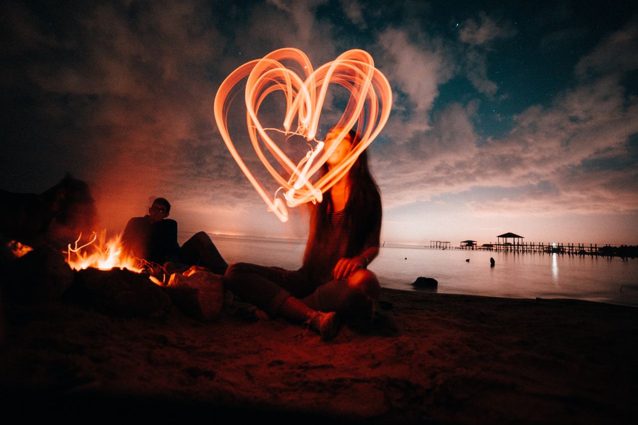 woman sitting on sand near bonfire