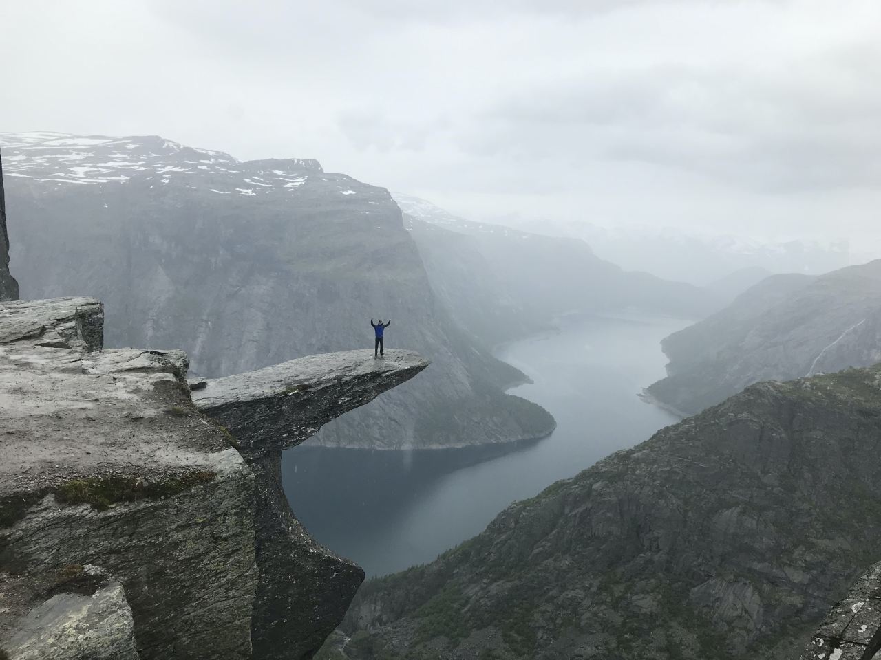 person standing on rock formation near river during daytime