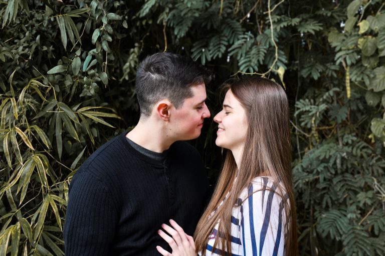 man in black sweater kissing woman in white and blue stripe shirt