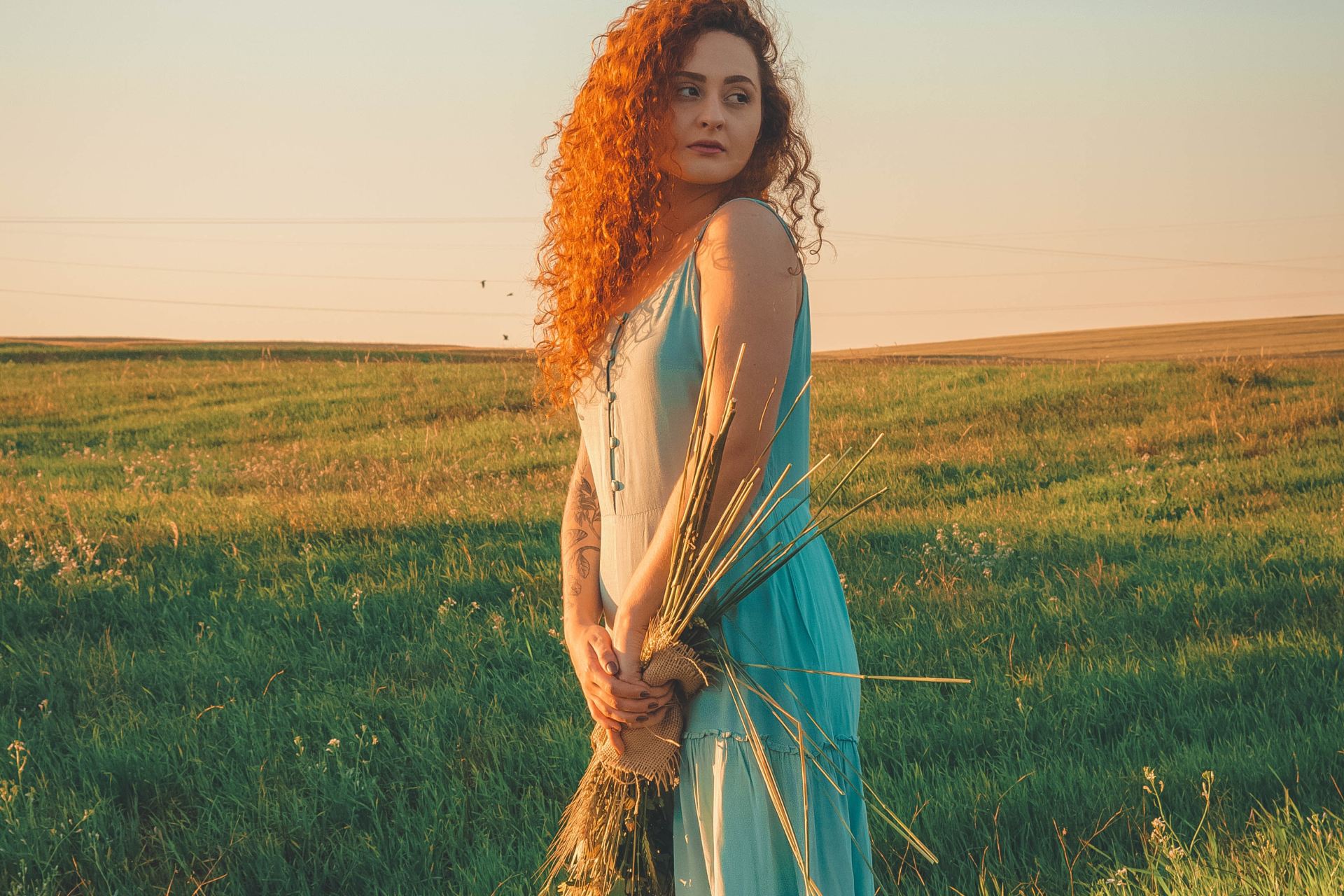 woman in blue sleeveless dress standing on green grass field during daytime