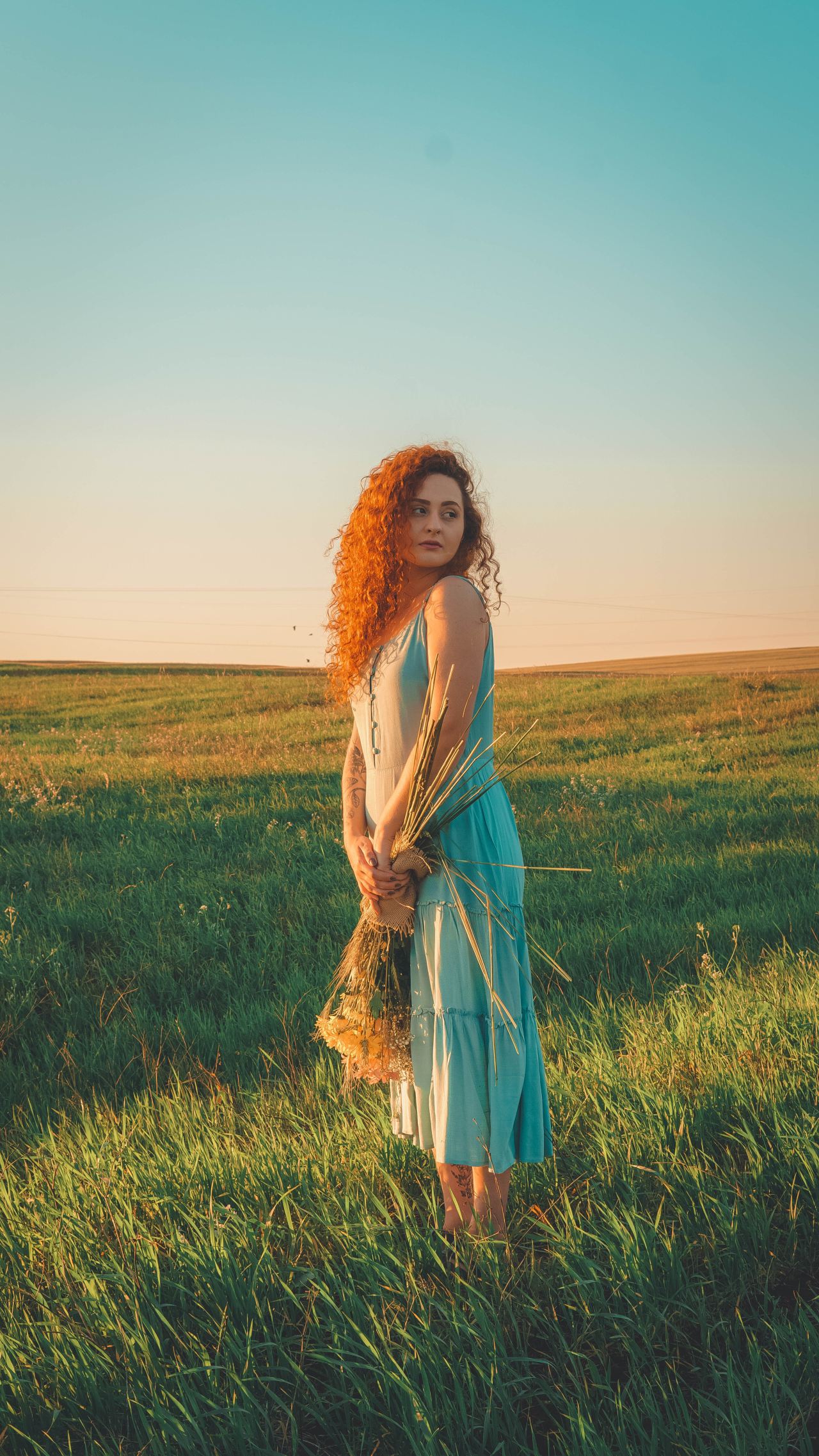 woman in blue sleeveless dress standing on green grass field during daytime