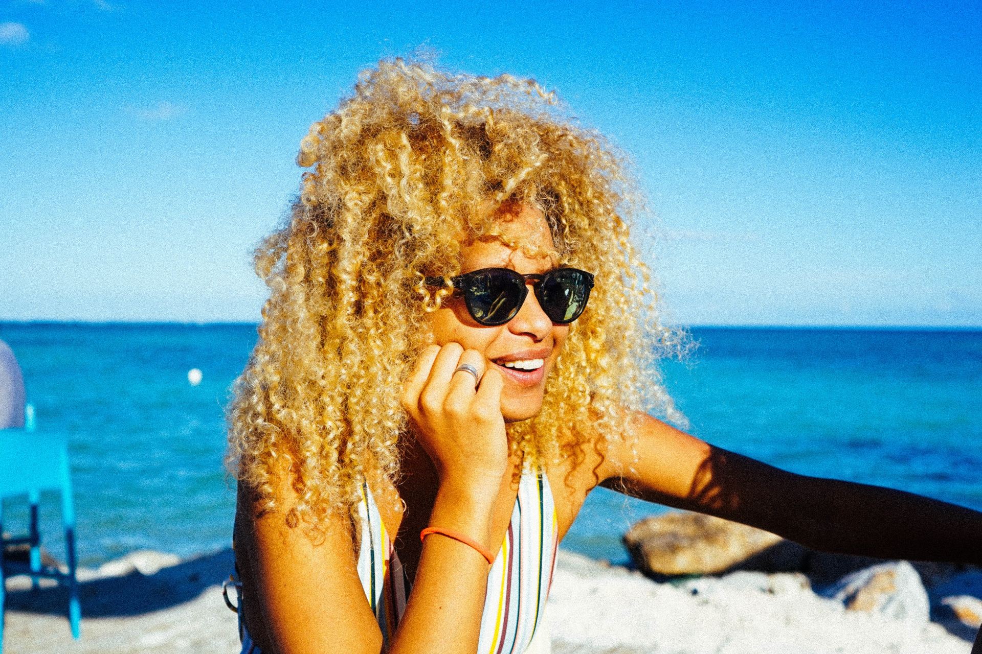 smiling woman beside dining table near beach