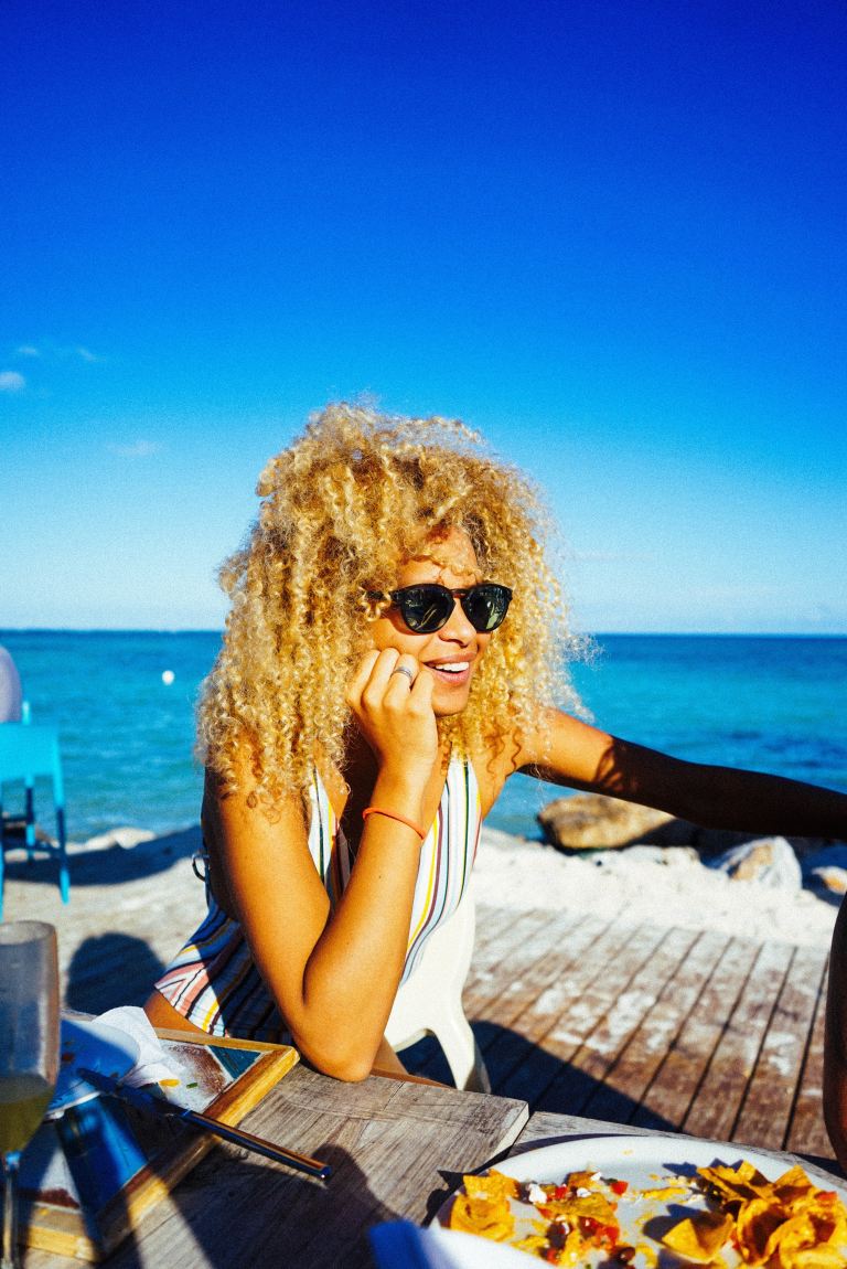 smiling woman beside dining table near beach