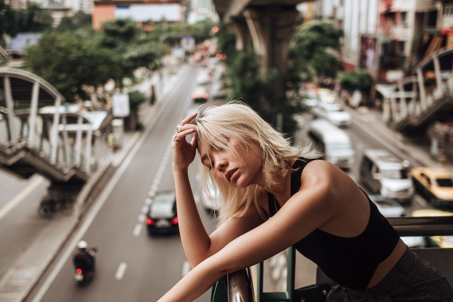 woman in black tank top leaning on gray metal railings during daytime