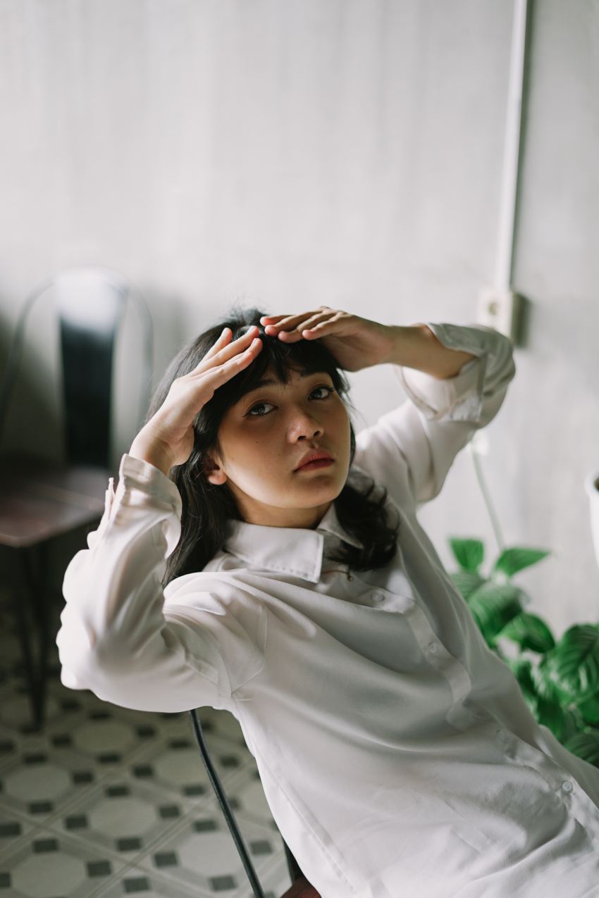 woman in white dress shirt covering her face with her hands