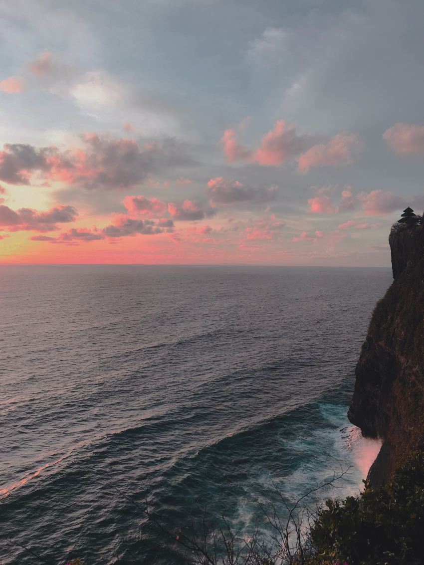 body of water near brown rock formation during sunset