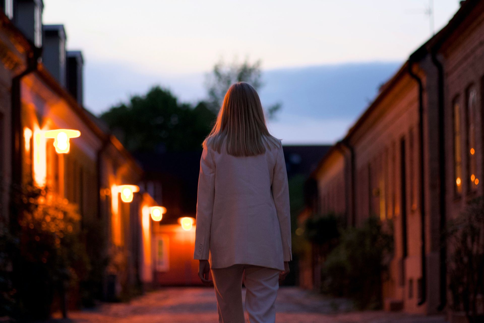 woman in white long sleeve shirt and gray pants standing on brown brick pathway during sunset