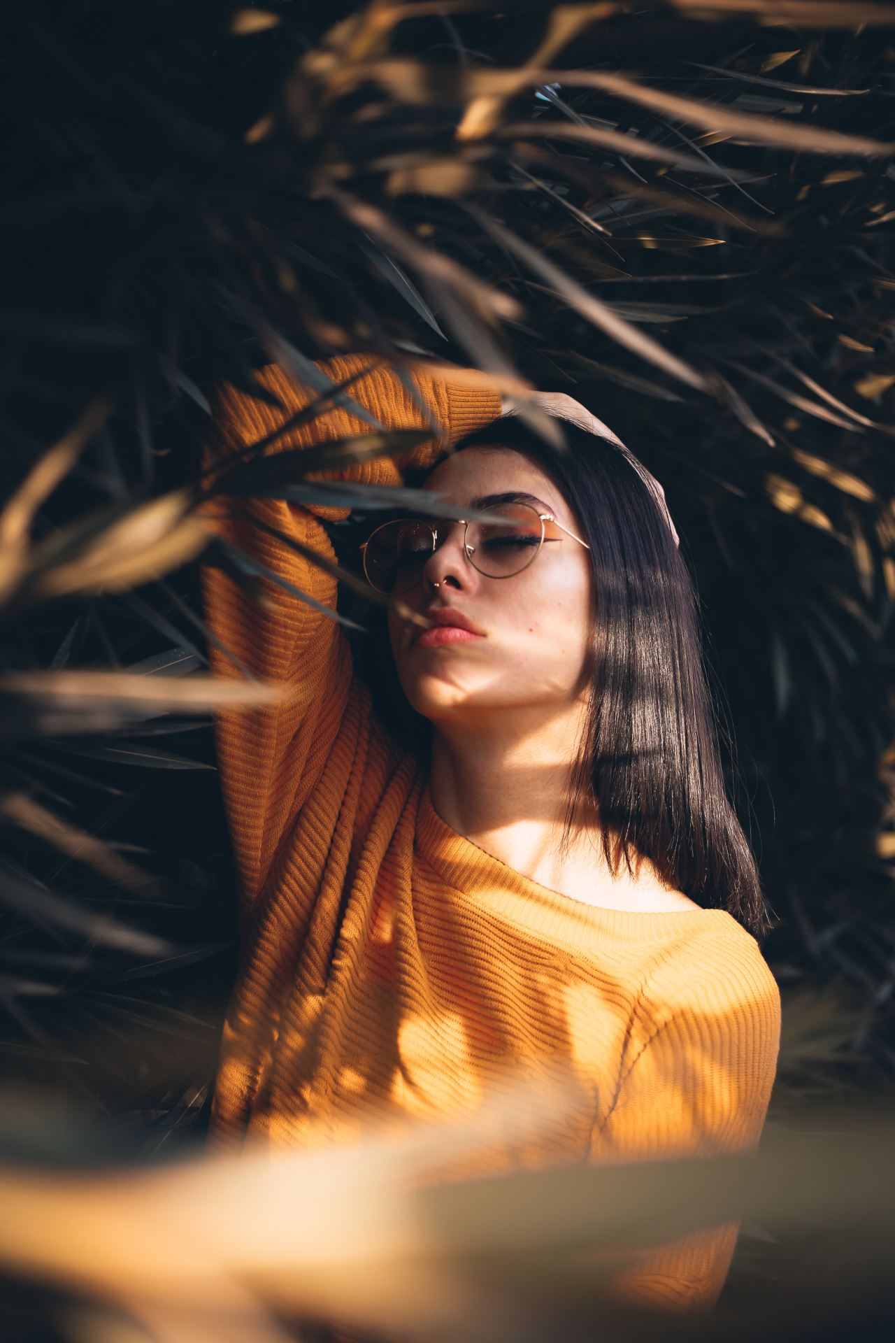 woman holding her head white standing in the middle of plants