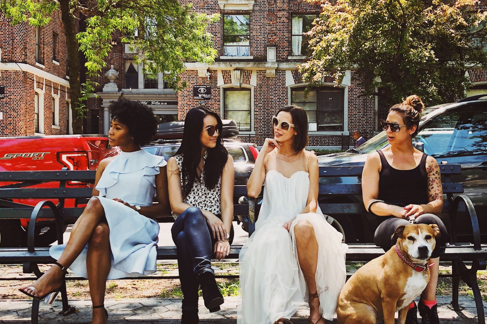 four women sitting on black steel bench during daytime