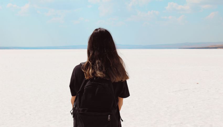 woman facing white field with backpack at daytime