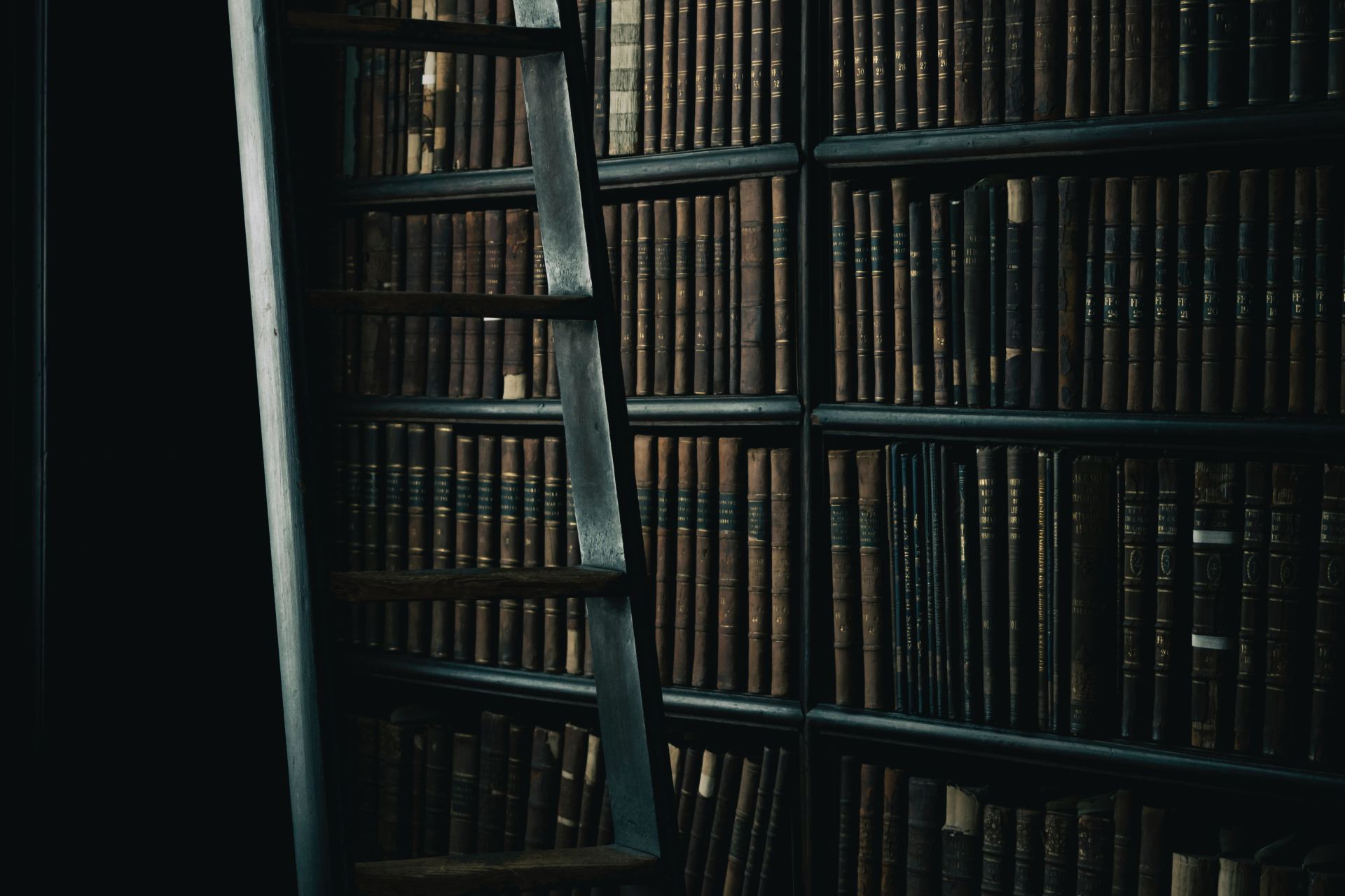 black wooden ladder beside brown wooden bookshelf