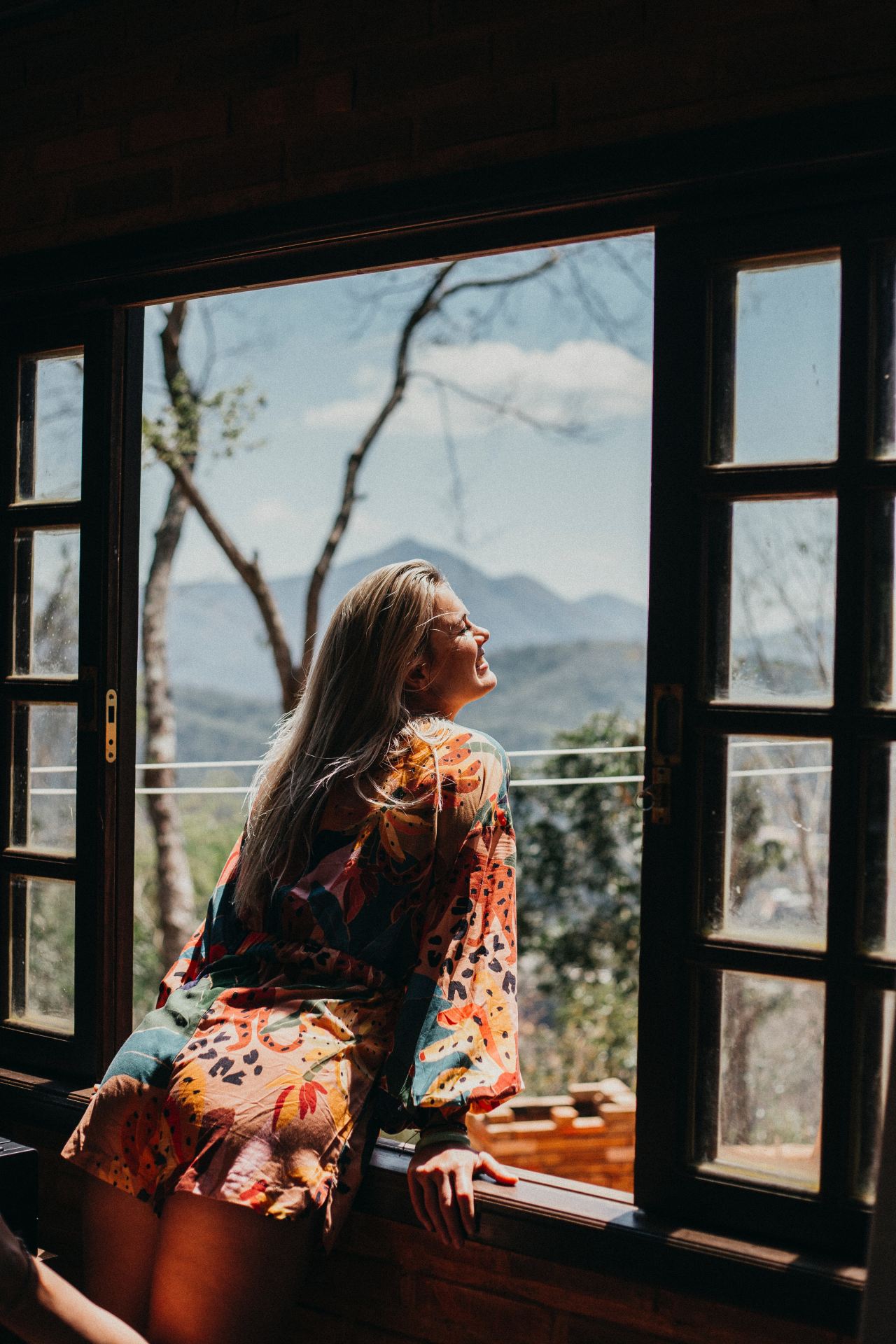 woman in red and white floral long sleeve shirt sitting on brown wooden chair