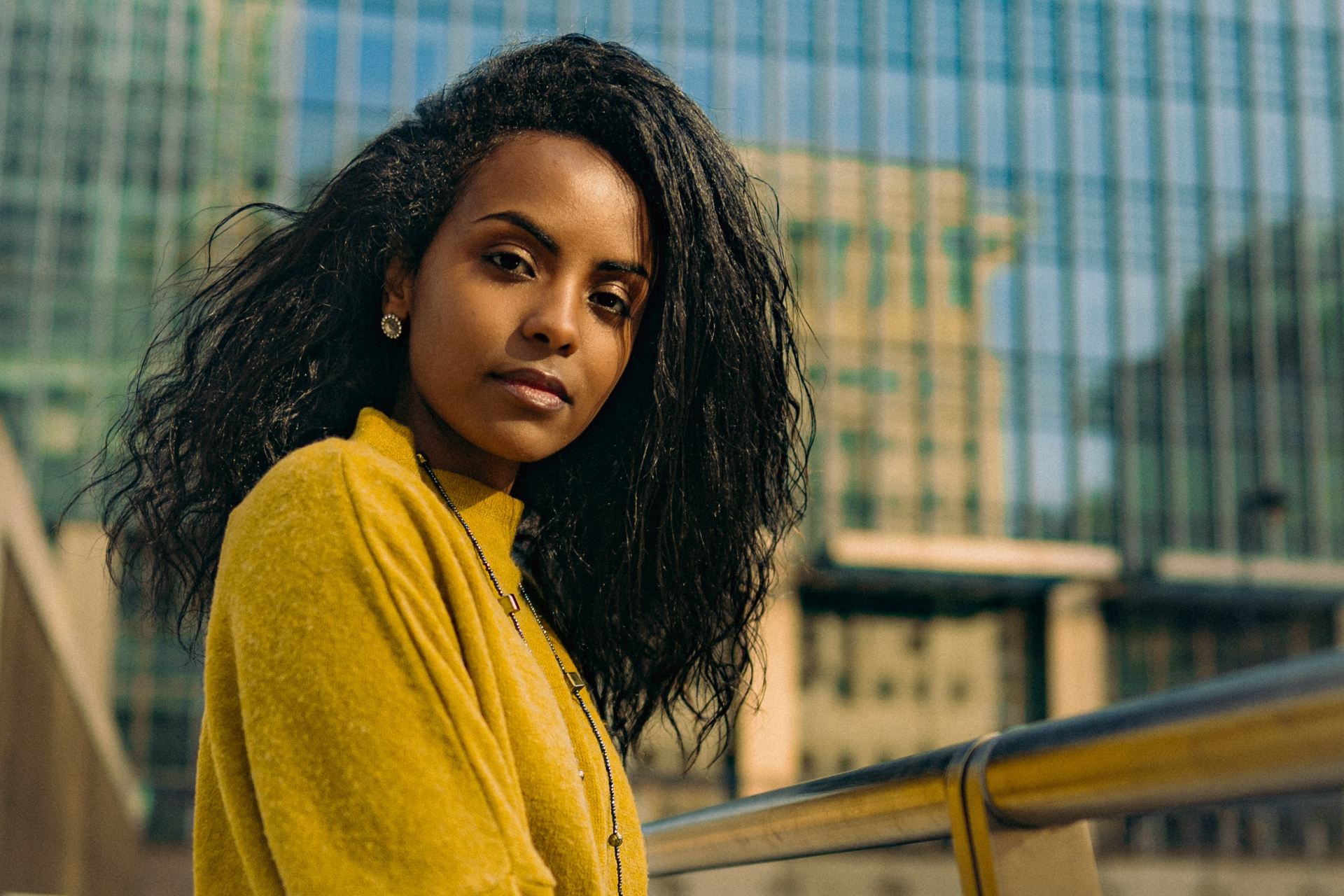 woman in yellow sweater standing beside brown metal railings