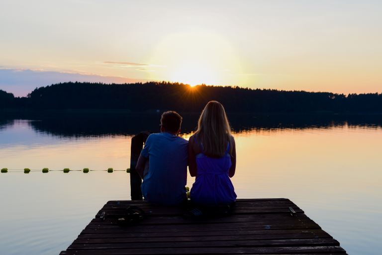 2 women sitting on dock during daytime