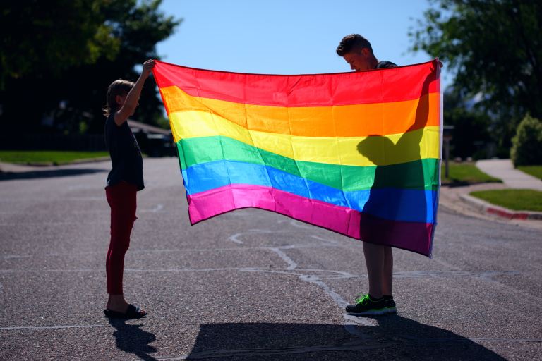 man and girl holding rainbow flag