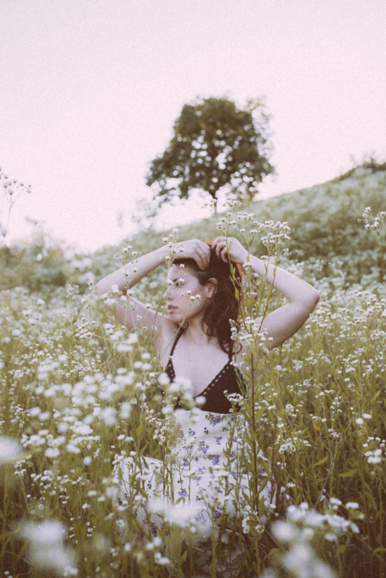 woman in blue and white floral spaghetti strap top standing on green grass field during daytime