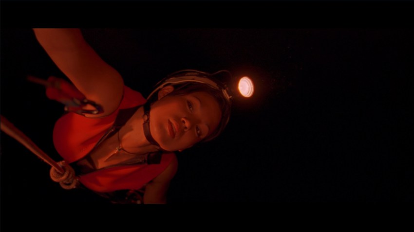 Juno swings across a pit in The Descent (2005).