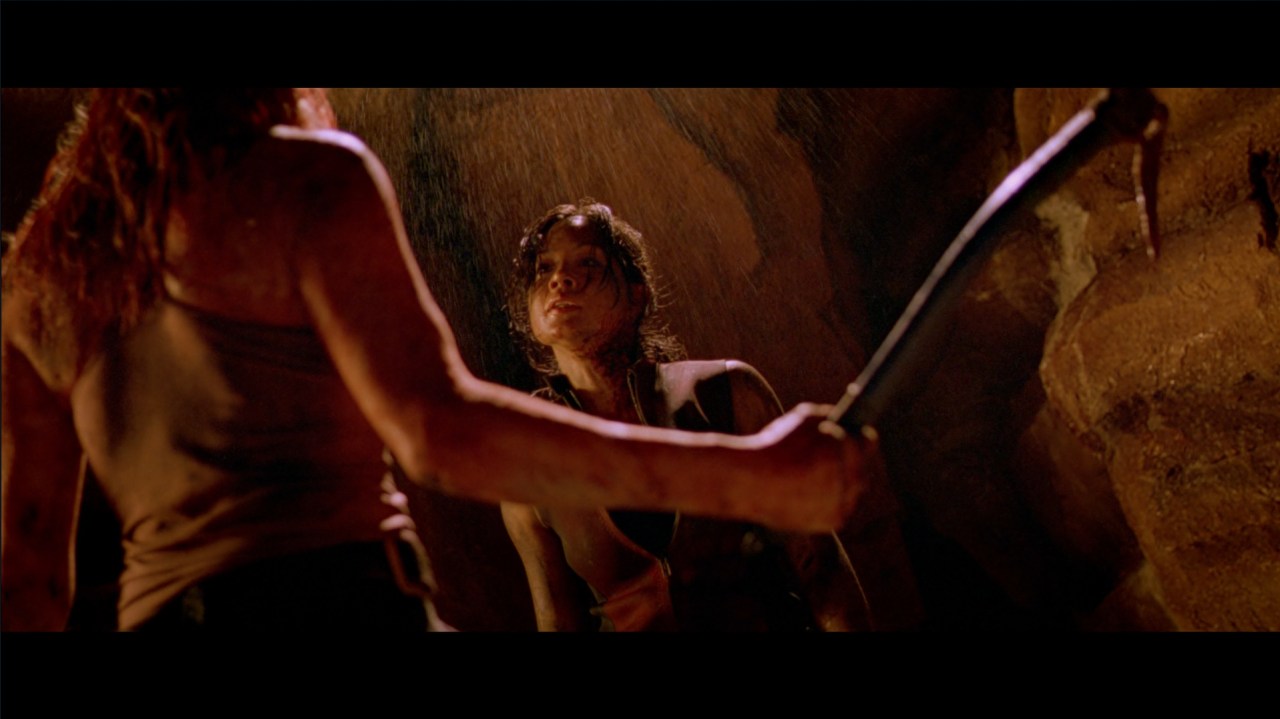 Sarah brandishes a pickaxe towards Juno in The Descent (2005).