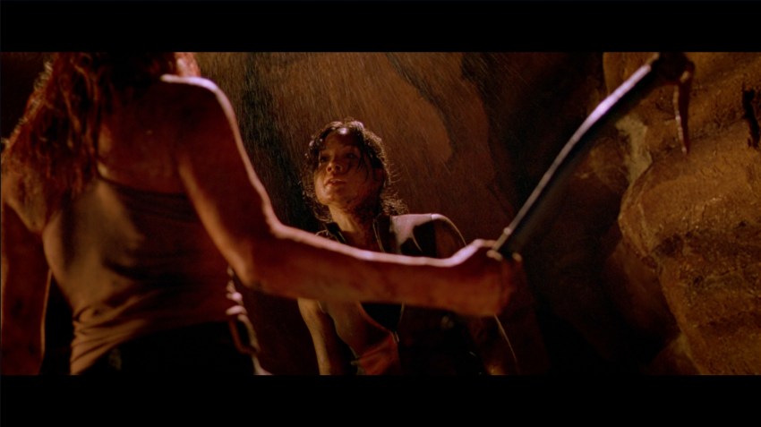 Sarah brandishes a pickaxe towards Juno in The Descent (2005).