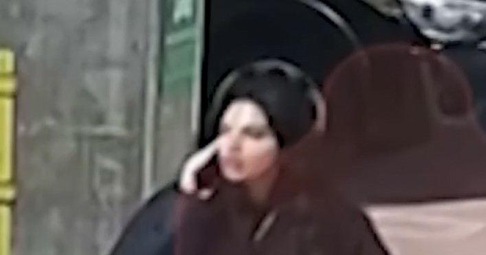 Surveillance footage still of Huda Mustafa walking through an apartment complex while on her phone