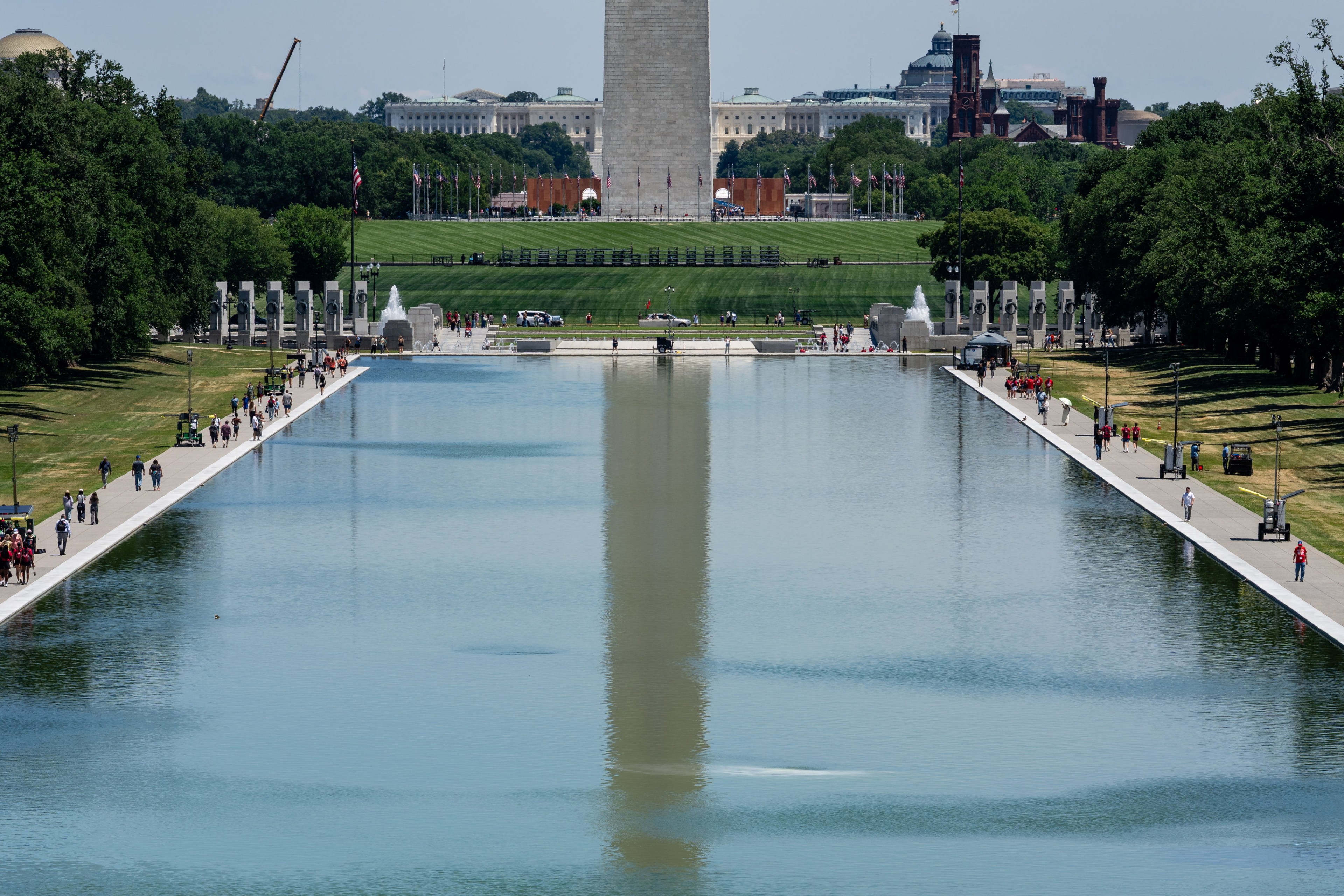 Wide view of the Lincoln Memorial Reflecting Pool reflecting the Washington Monument, with the WWII Memorial and U.S. Capitol visible in the background on a sunny day.