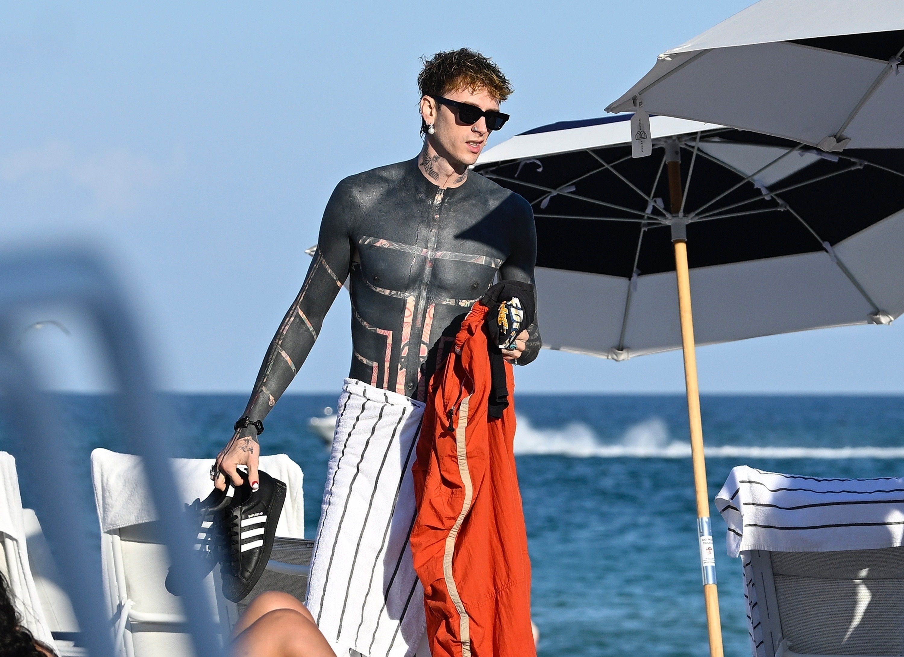 Machine Gun Kelly shirtless on a beach in Miami with friends