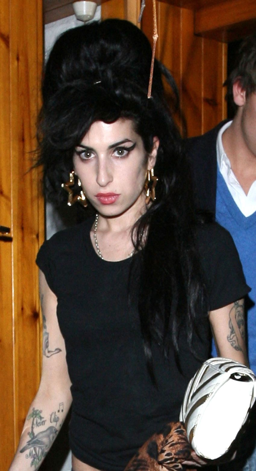 Amy Winehouse and Tyler James leaving a building at night, with Amy in a black t-shirt, blue jeans, and pink ballet pumps.