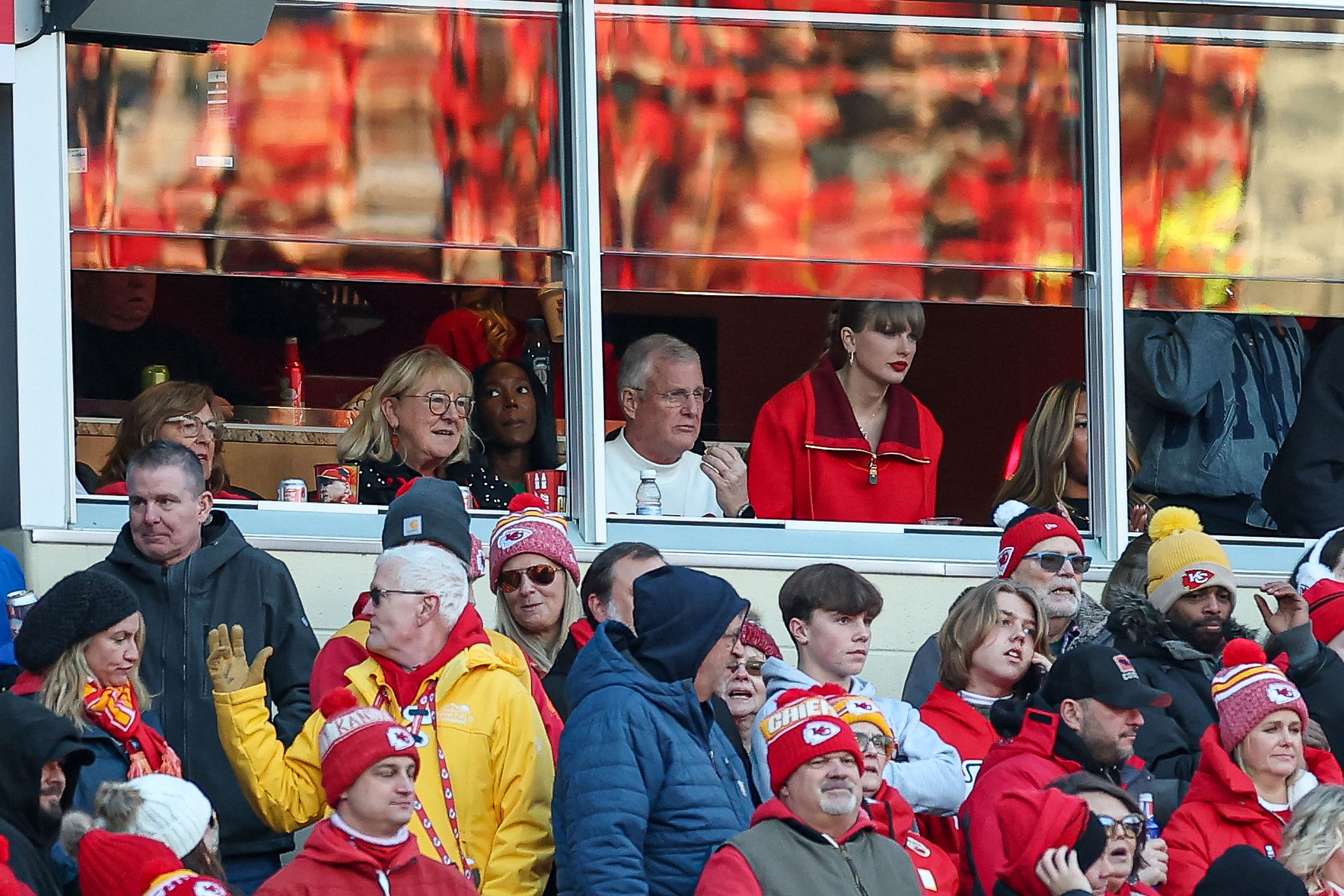 Donna Kelce, Scott Swift, and Taylor Swift sitting together in the stands at GEHA Field at Arrowhead Stadium