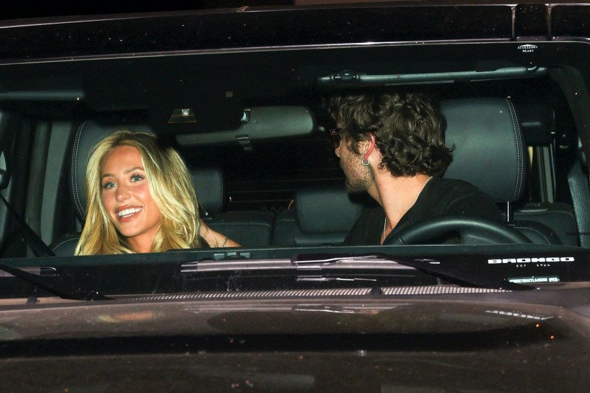 A smiling blonde woman and a dark-haired man sitting together inside a Ford Bronco at night.