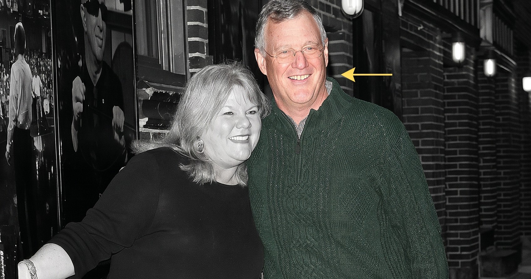 Man in green cable-knit sweater and woman in black outfit smiling together outside the Late Show with David Letterman entrance.