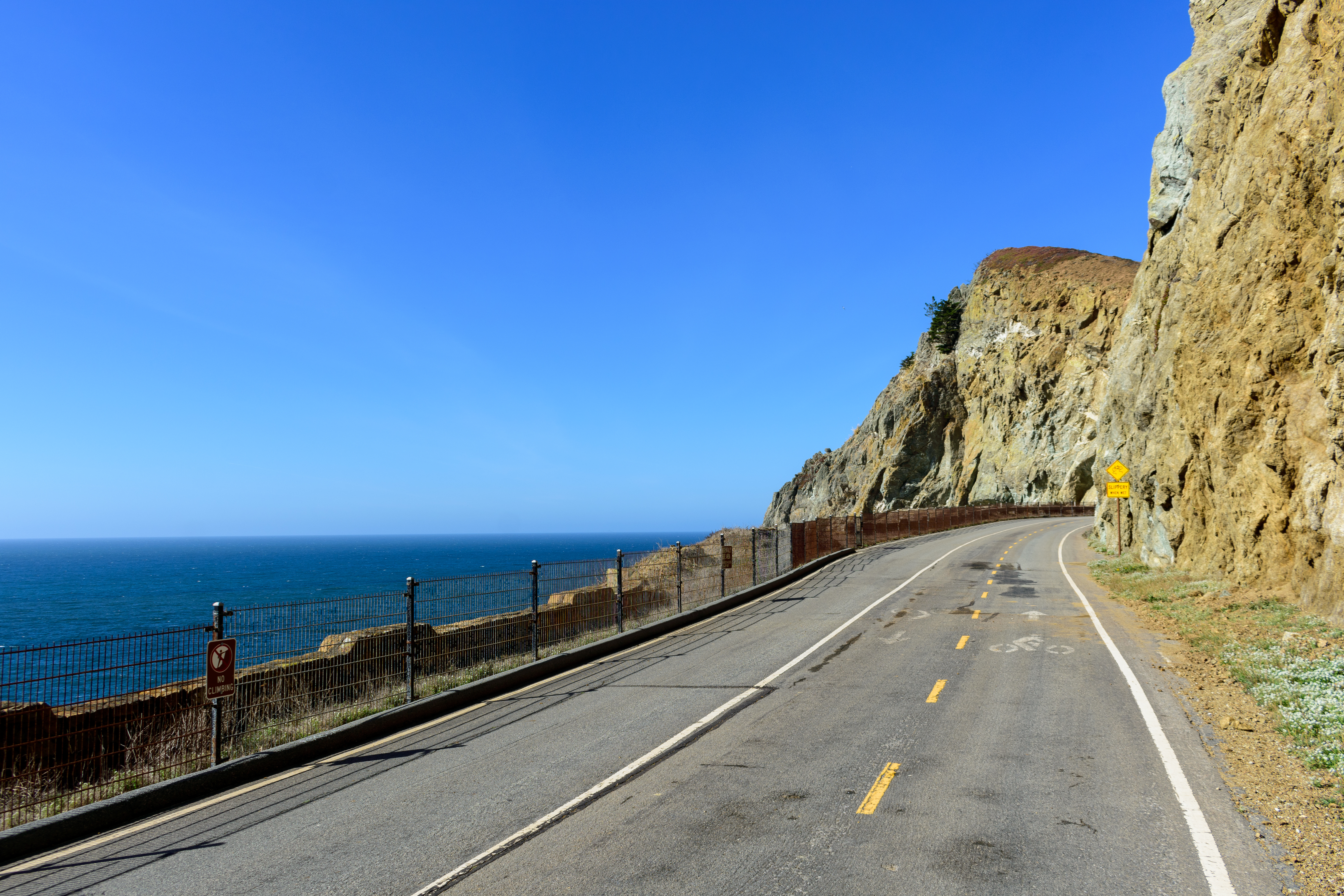 Winding mountain road along Devils Slide trail with steep cliffs on one side and the ocean on the other