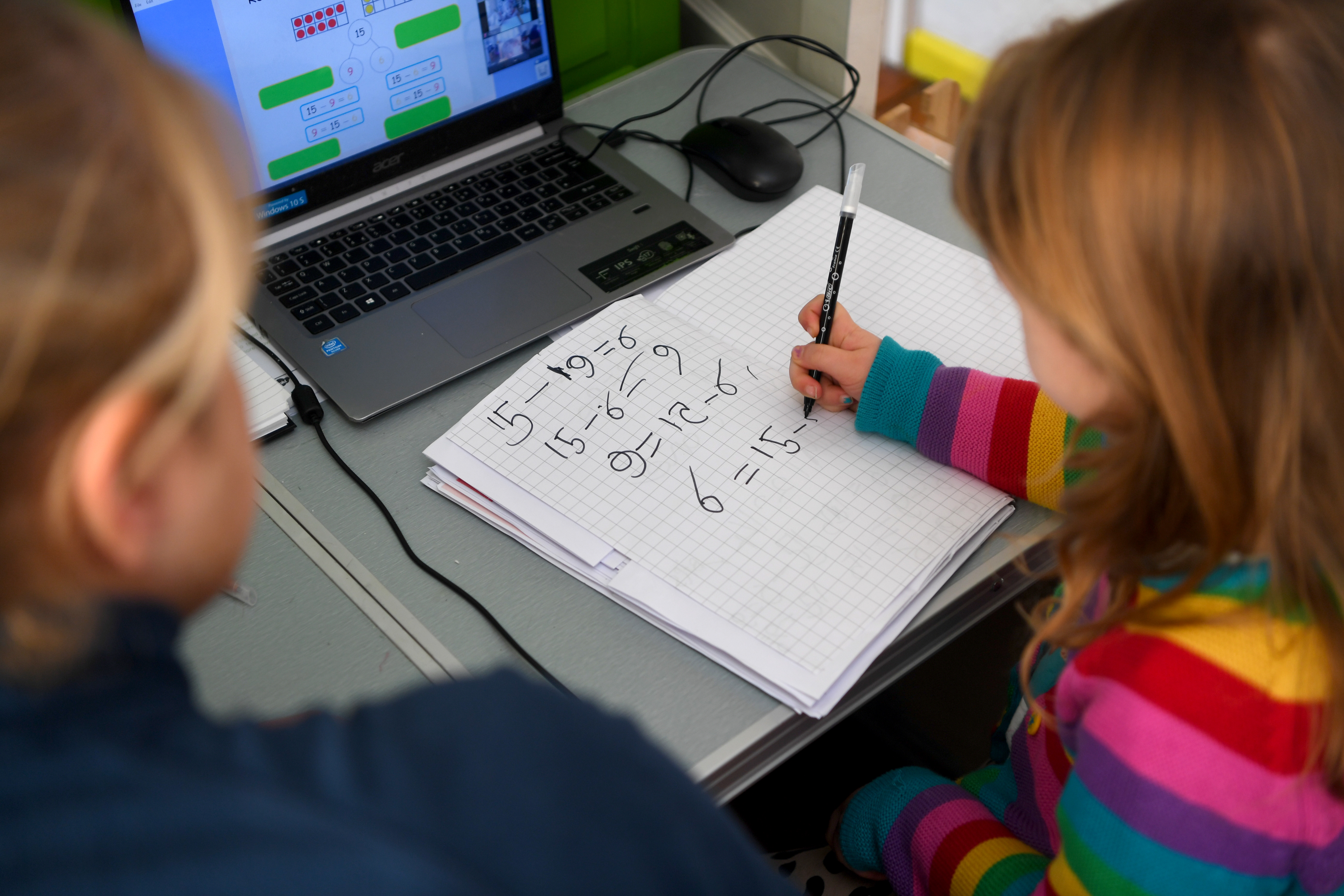 A young girl sitting at a desk in her bedroom doing math schoolwork at home
