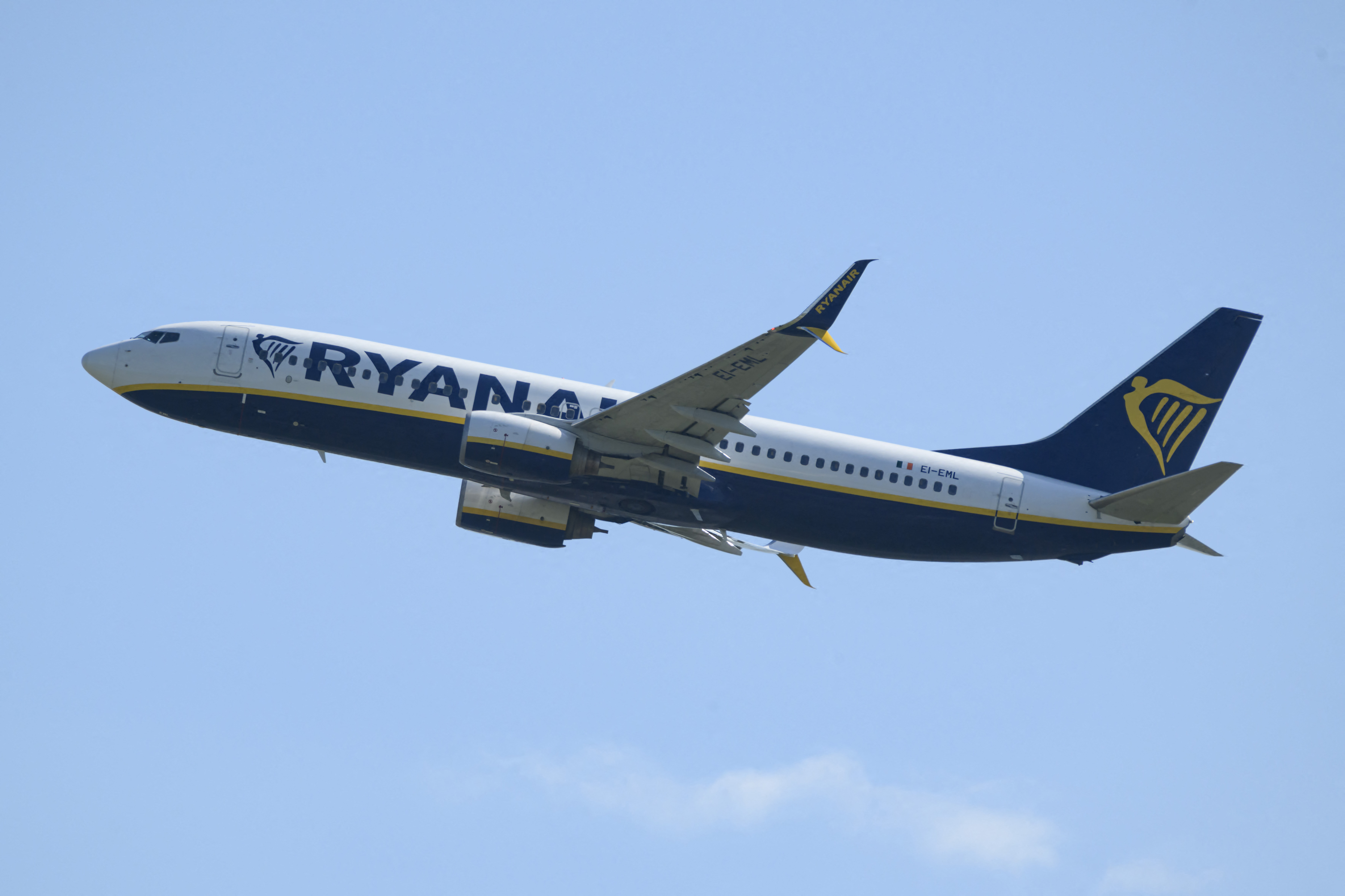 A Ryanair Boeing 737 aircraft with blue and white livery and registration EI-EML climbs into a clear blue sky after takeoff.