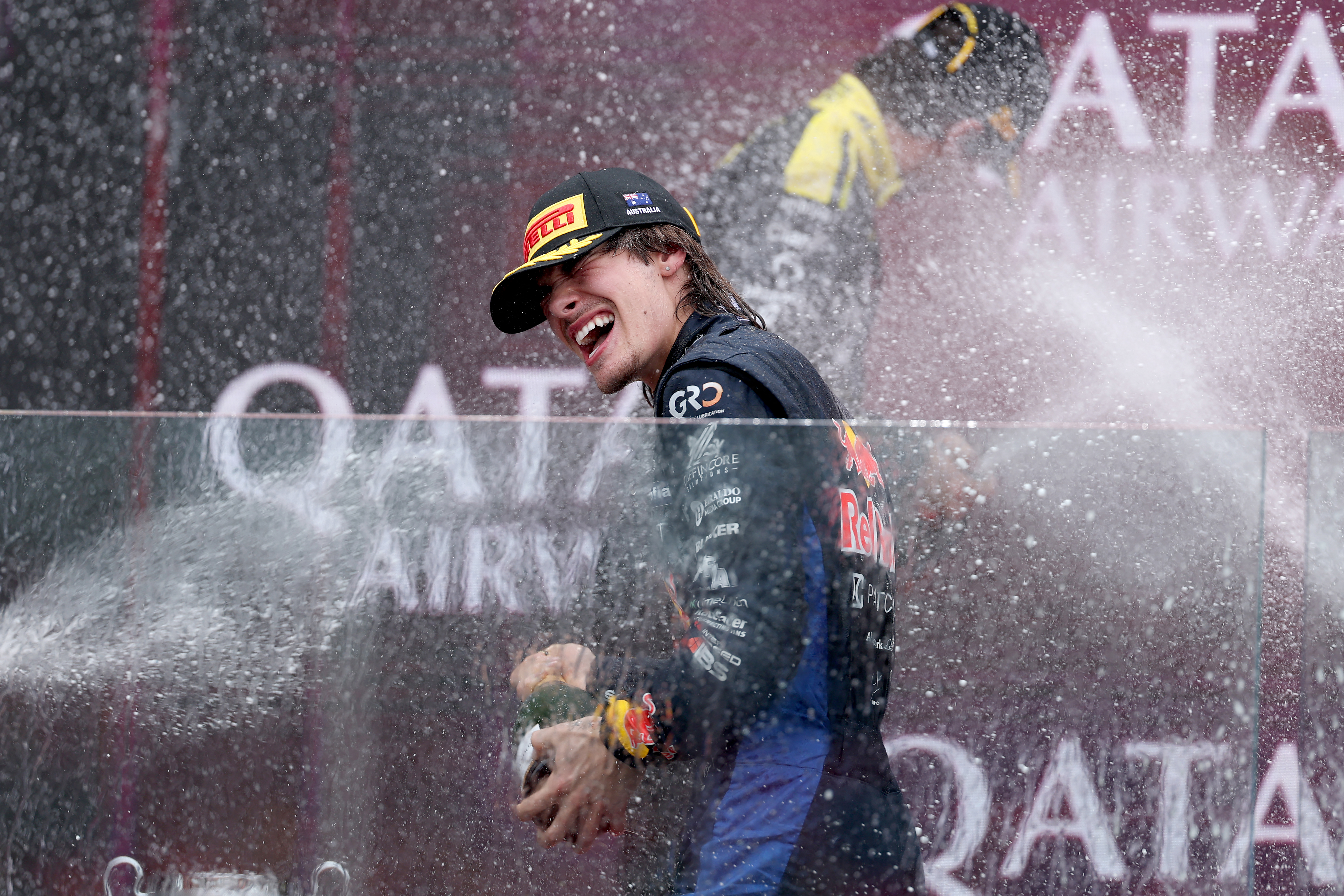 Nikola Tsolov in a Red Bull race suit spraying champagne on the podium at the Albert Park Formula 2 race.