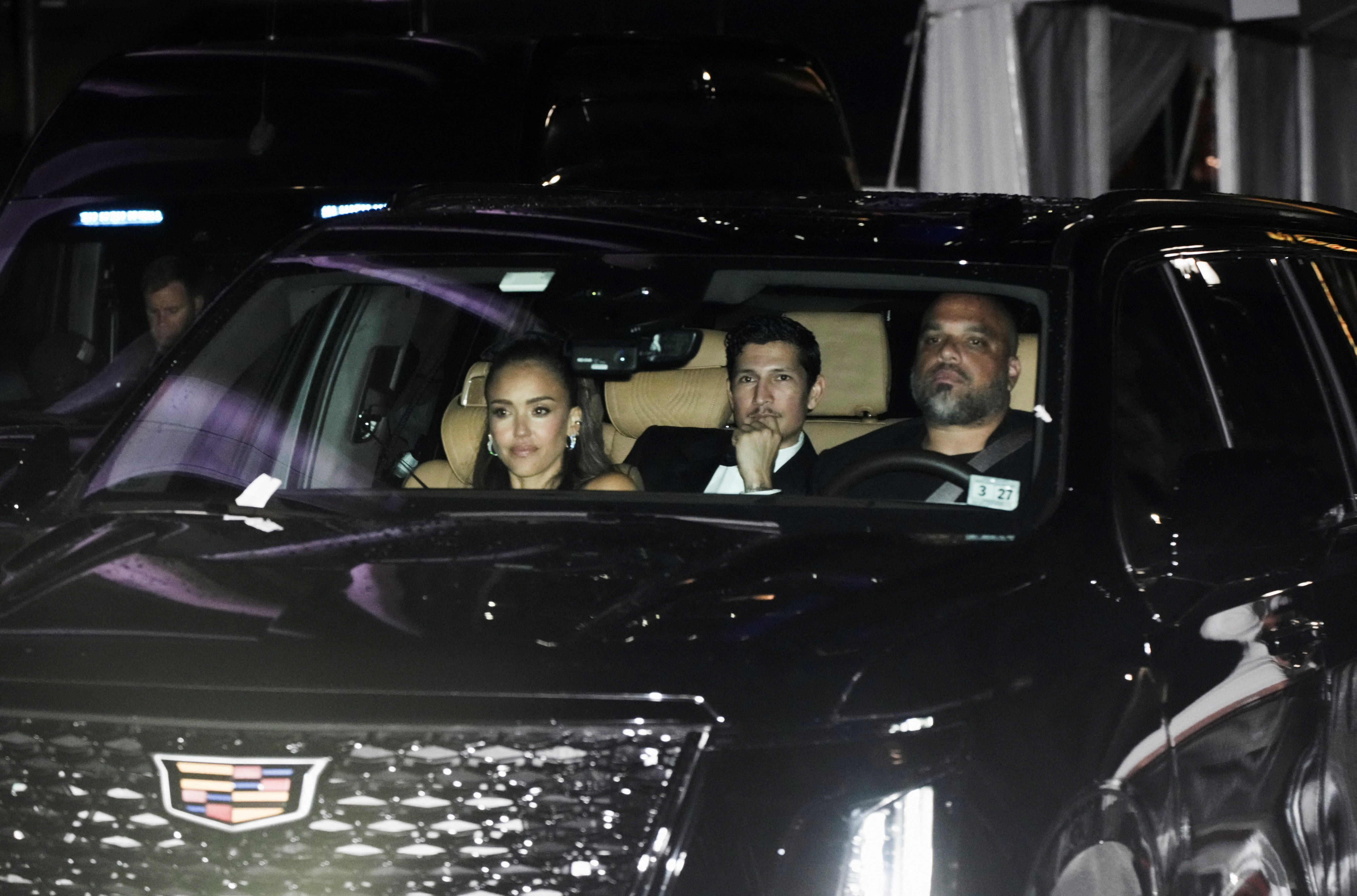 Jessica Alba and Danny Ramirez seated in the back of a black Cadillac SUV at night outside Madison Square Garden.