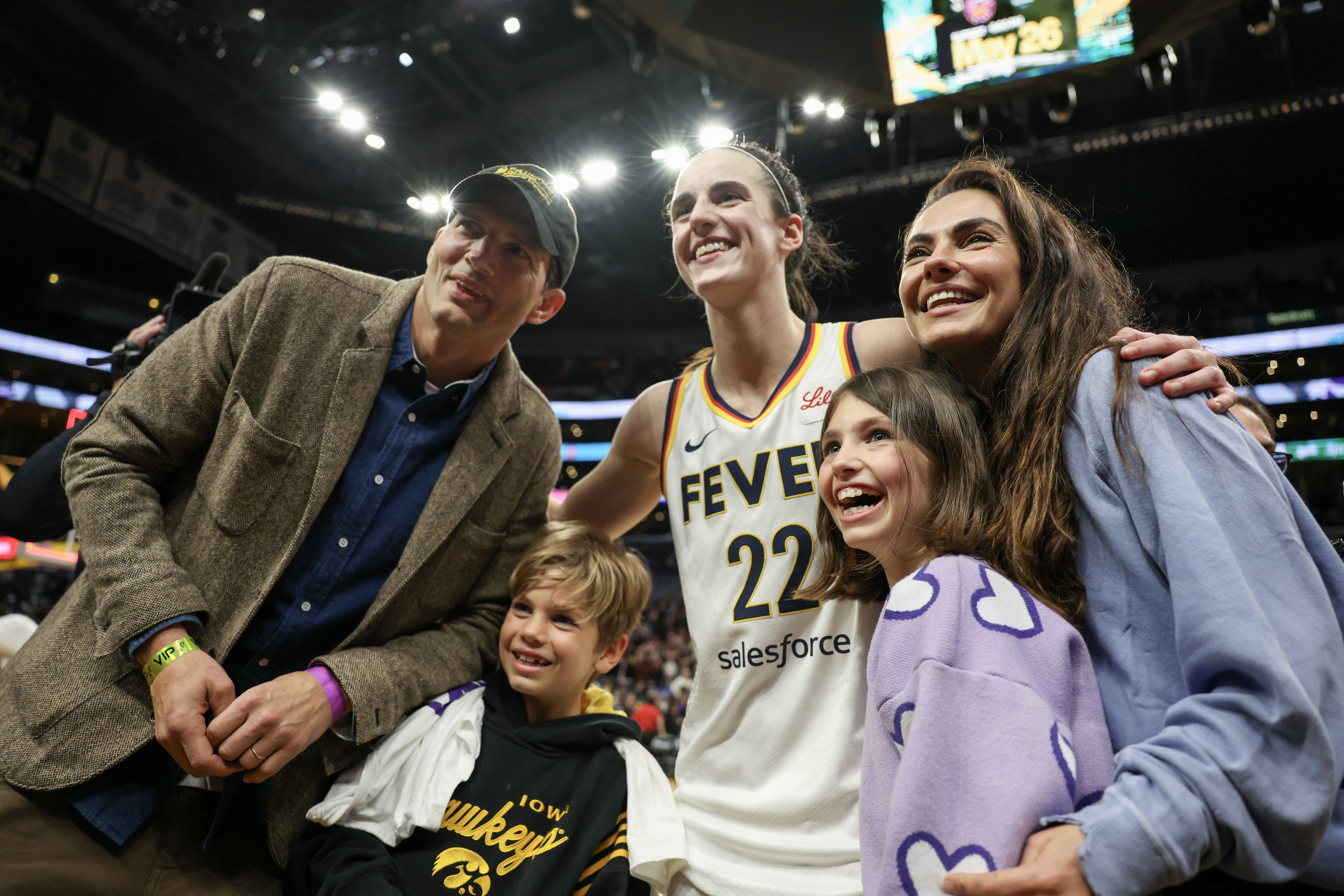 Caitlin Clark posing with Ashton Kutcher and Mila Kunis at Crypto.com Arena after an Indiana Fever game