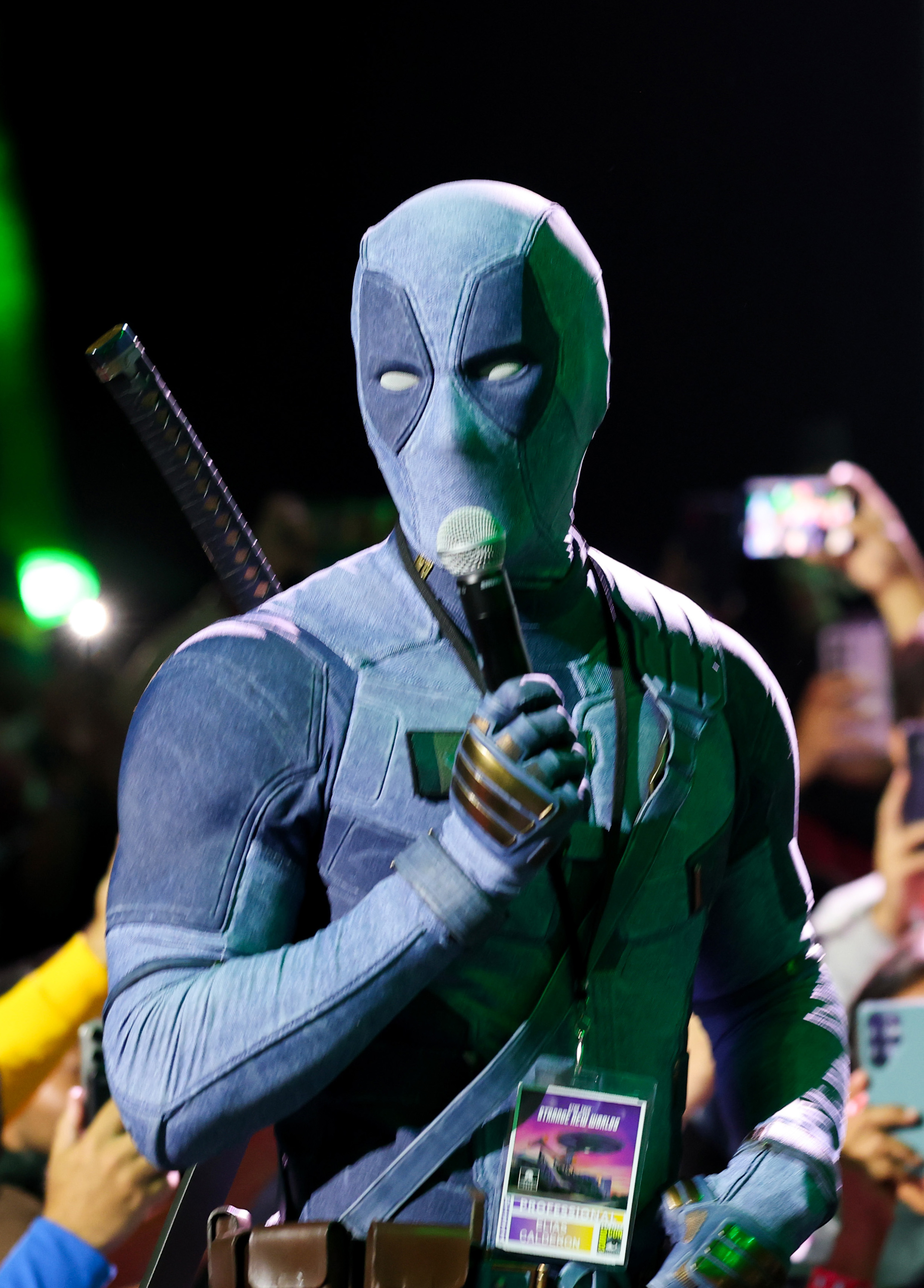 Ryan Reynolds dressed in a Deadpool suit speaking at the Marvel Studios Hall H panel at San Diego Comic-Con