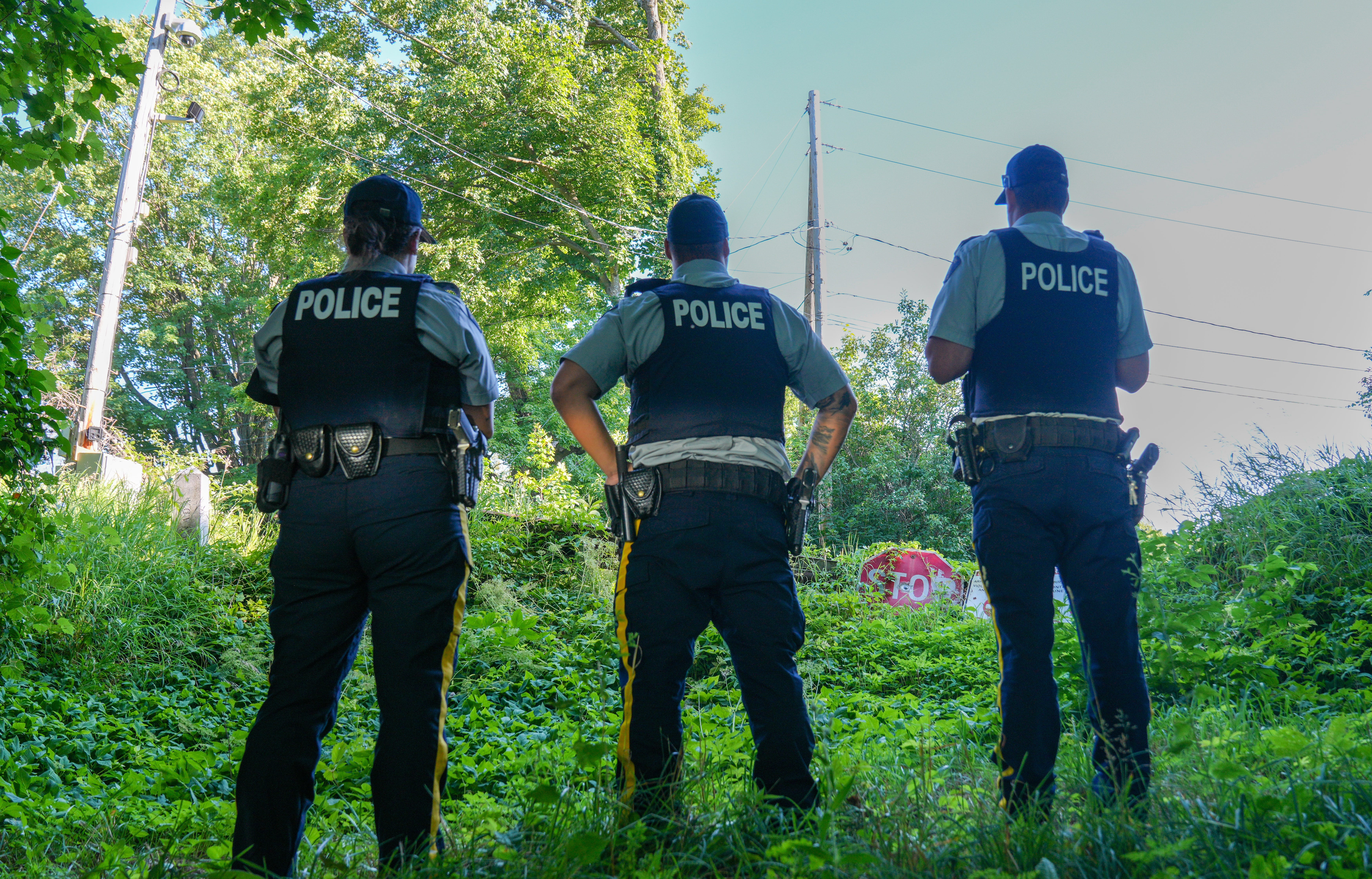 Border-patrolling members of the Royal Canadian Mounted Police, from left, Cpl. Marie-Pierre Guertin, Cpl. Samuel Perreault-Magny, and Sgt. Jonathan Maheu, stand at a dead-end road on the Canadian sid
