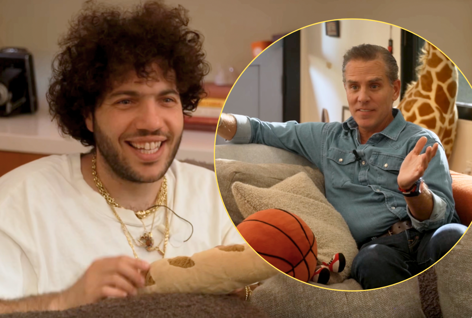 Curly-haired man in a white t-shirt and gold chain smiling on a couch in front of a bookshelf.
