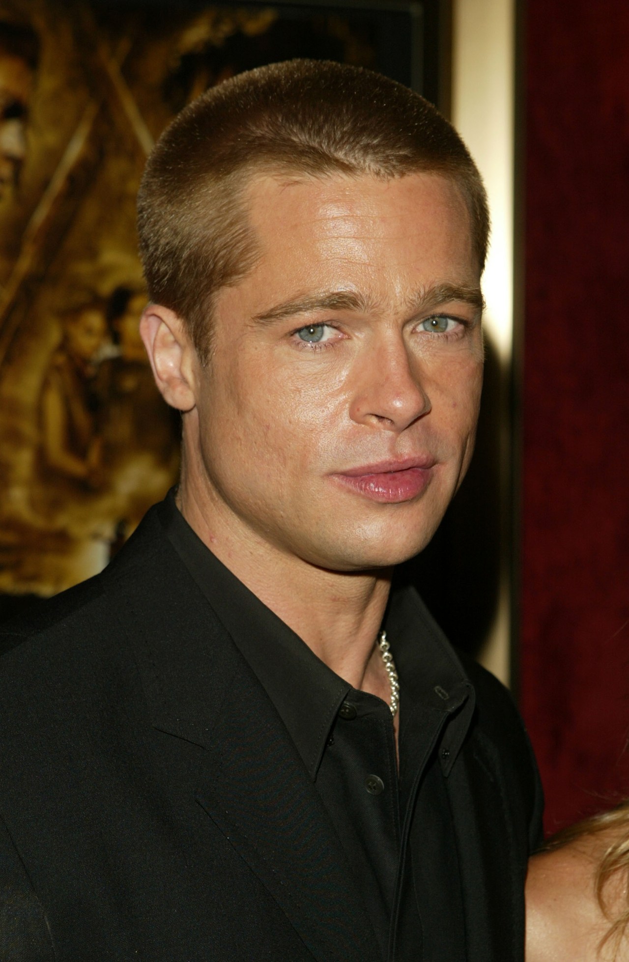 Close-up of a man with short blond hair and blue eyes in a black shirt at a movie premiere.