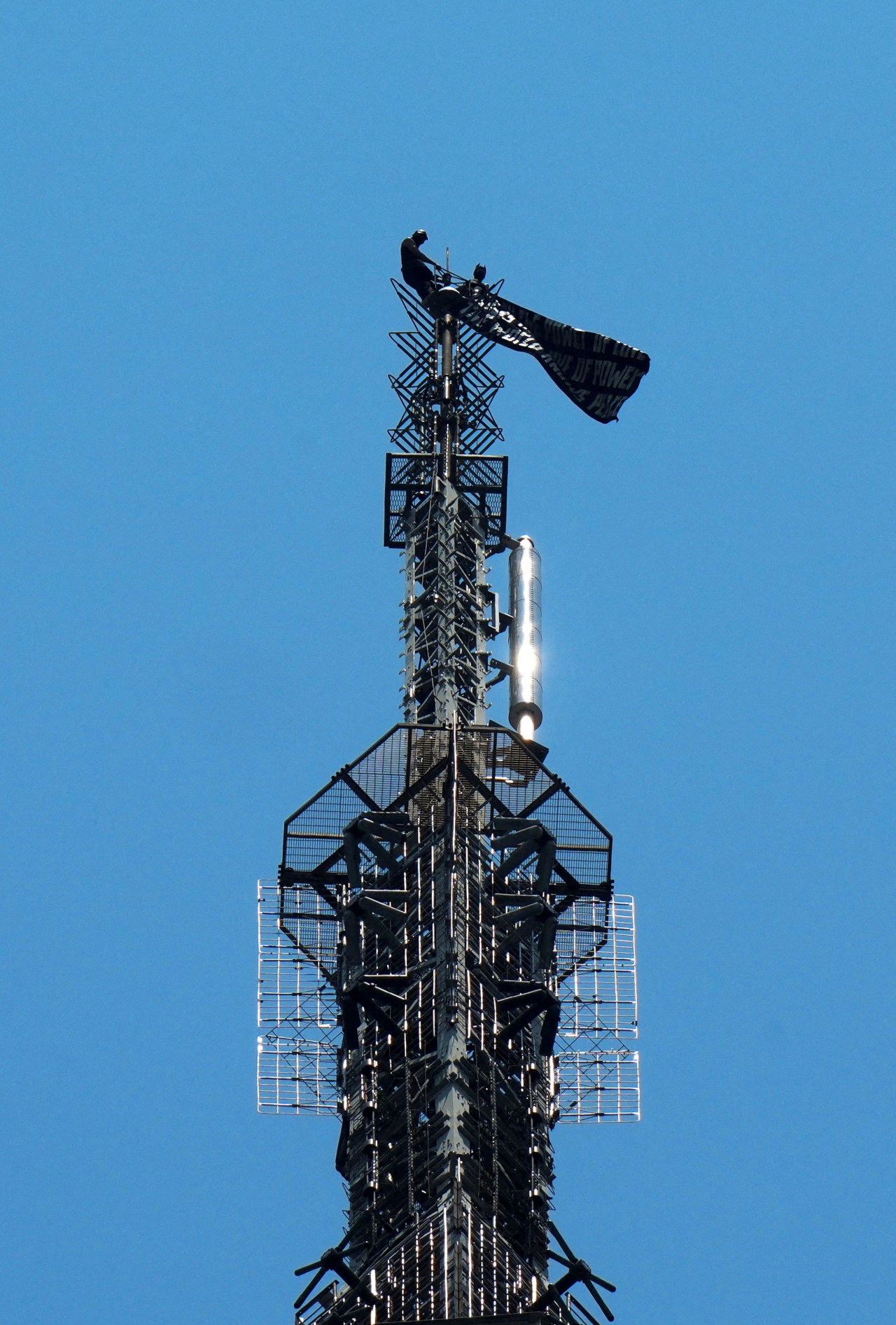 Two people displaying a banner during a protest on top of the Empire State Building in New York City