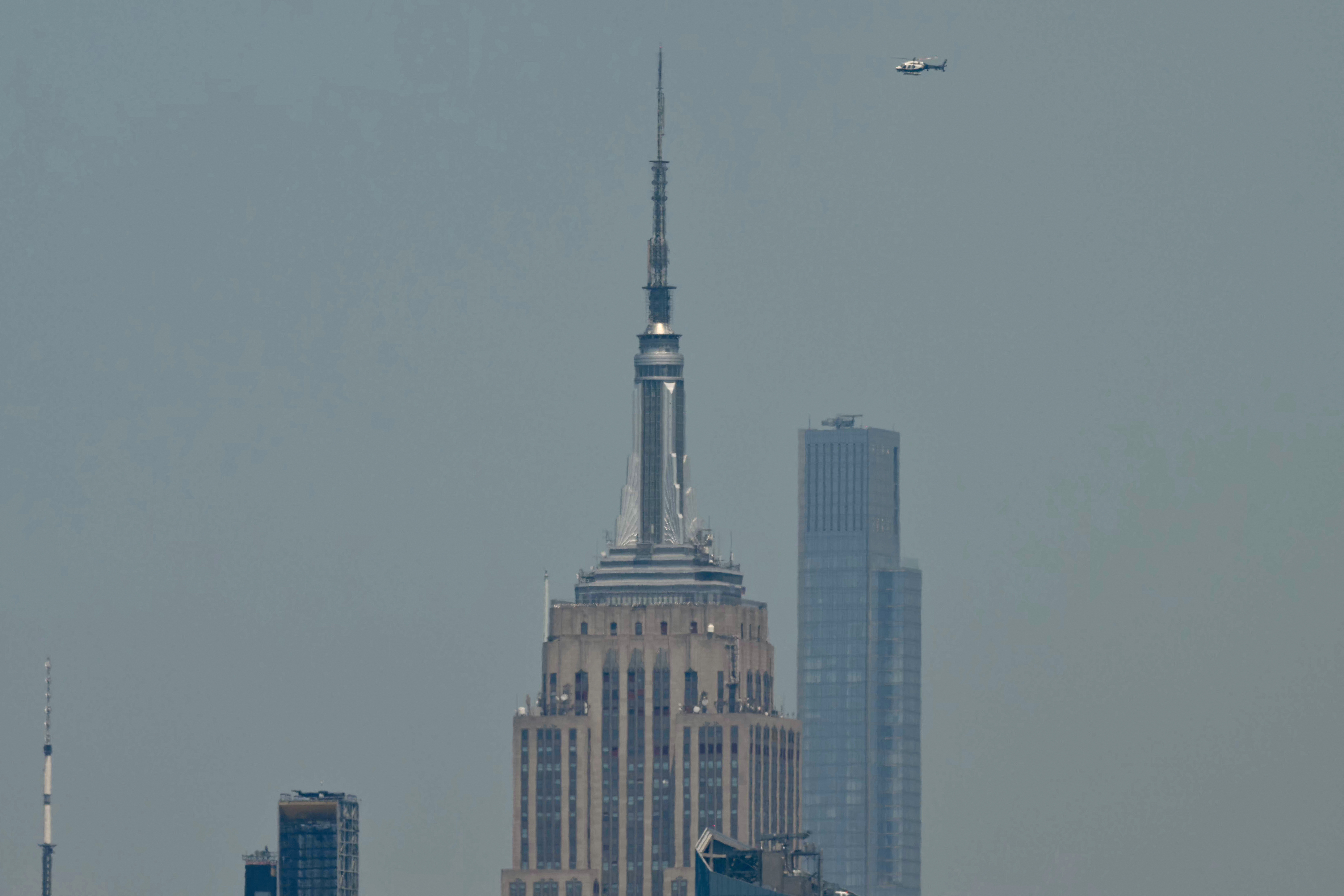 A helicopter flying near the top of the Empire State Building in New York City