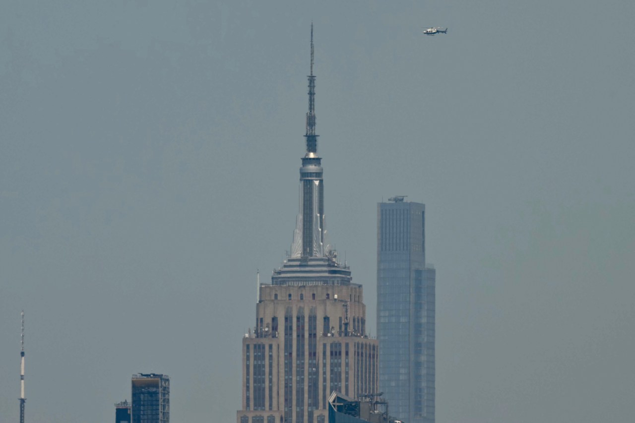 A helicopter flying near the top of the Empire State Building in New York City