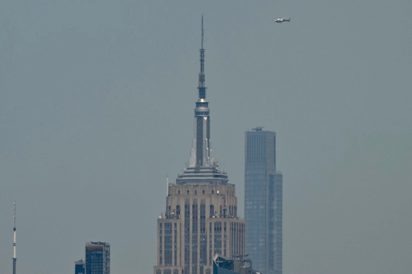 A helicopter flying near the top of the Empire State Building in New York City