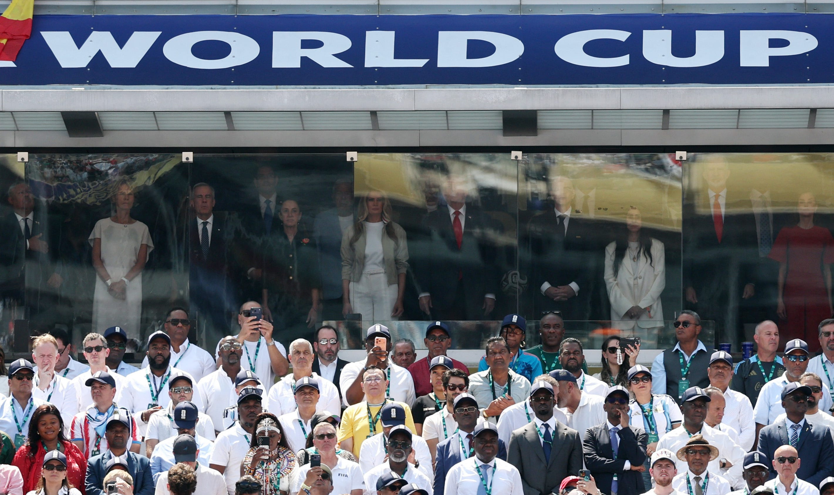 Donald Trump, Claudia Sheinbaum, and Mark Carney standing behind suite glass at the World Cup final