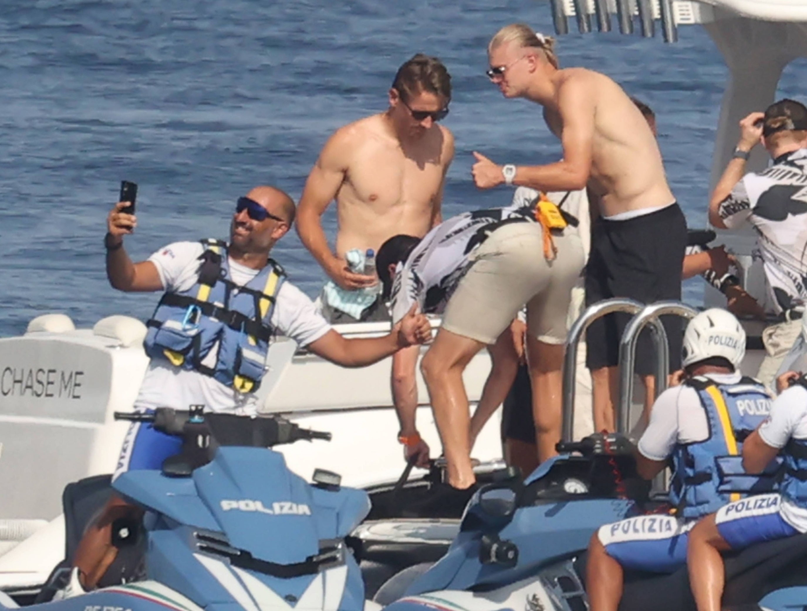 Erling Haaland shirtless on a yacht in Taormina, Sicily, holding his baby, with Sander Berge nearby