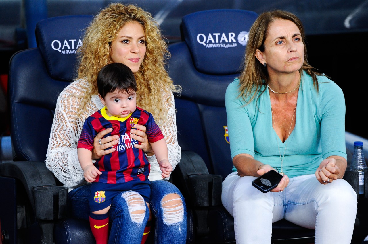 Shakira holding baby Milan dressed in an FC Barcelona kit while seated next to an older woman with brown hair at Camp Nou.