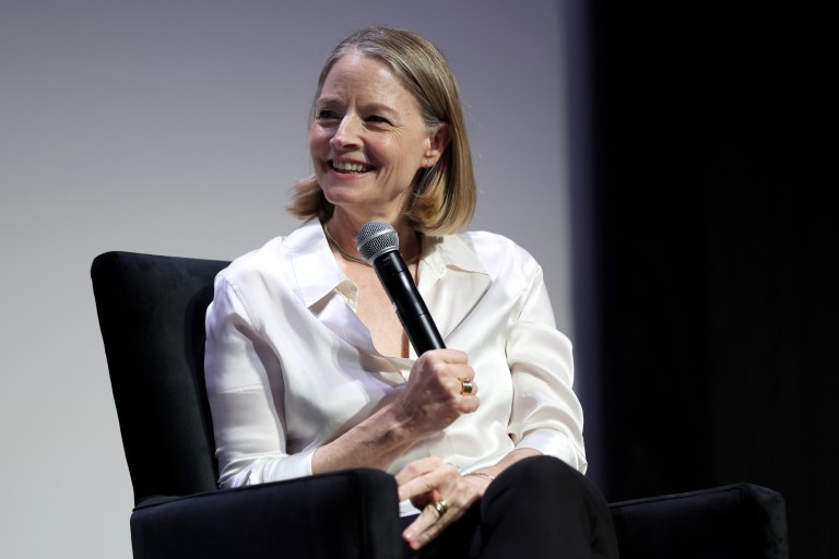 Jodie Foster seated and smiling while holding a microphone at a Tribeca Film Festival screening event.